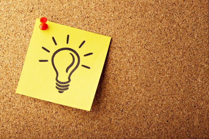 post it note with a lightbulb idea icon, pinned to a cork board
